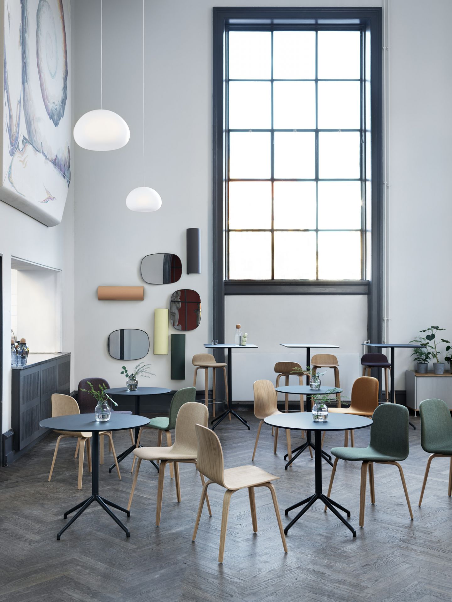 Innenraumansicht mit mehreren Visu Chair Wood Base Stühlen von Muuto in verschiedenen Farben und Holztönen.