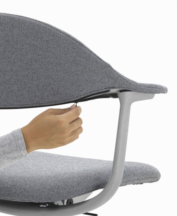Detailaufnahme: Hand öffnet Reißverschluss am grauen Mynt Bürodrehstuhl von Vitra, ergonomischer Arbeitsstuhl mit Stoffbezug.