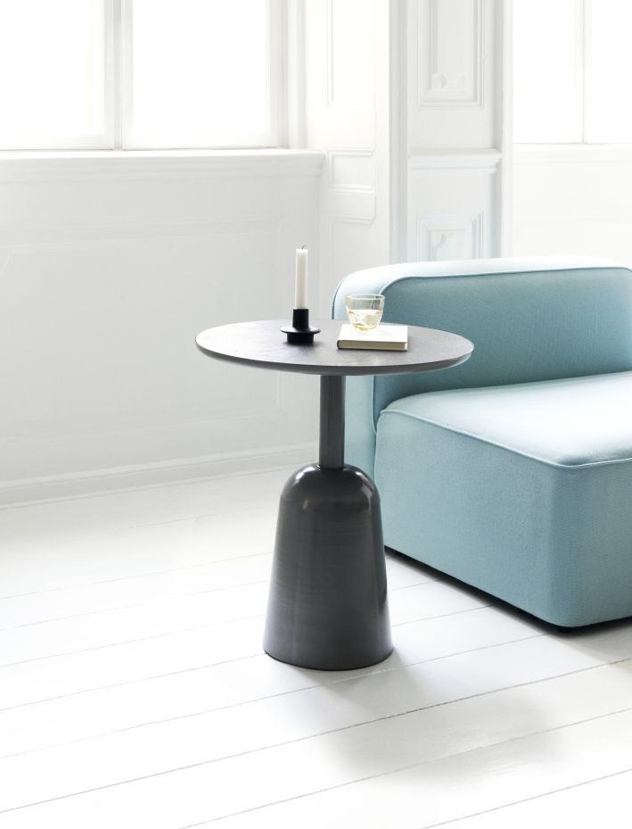 Grauer Normann Copenhagen Turn Table Beistelltisch neben einem hellblauen Sofa in einem hellen Raum.