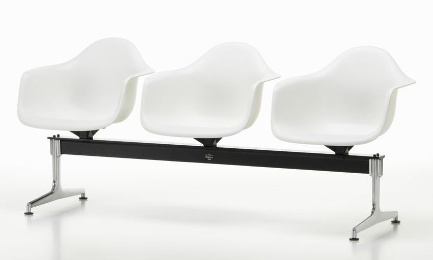 Eames Plastic Armchair RE auf Traverse von Vitra, Wartebank mit drei weißen Kunststoffschalen und schwarzem Gestell.