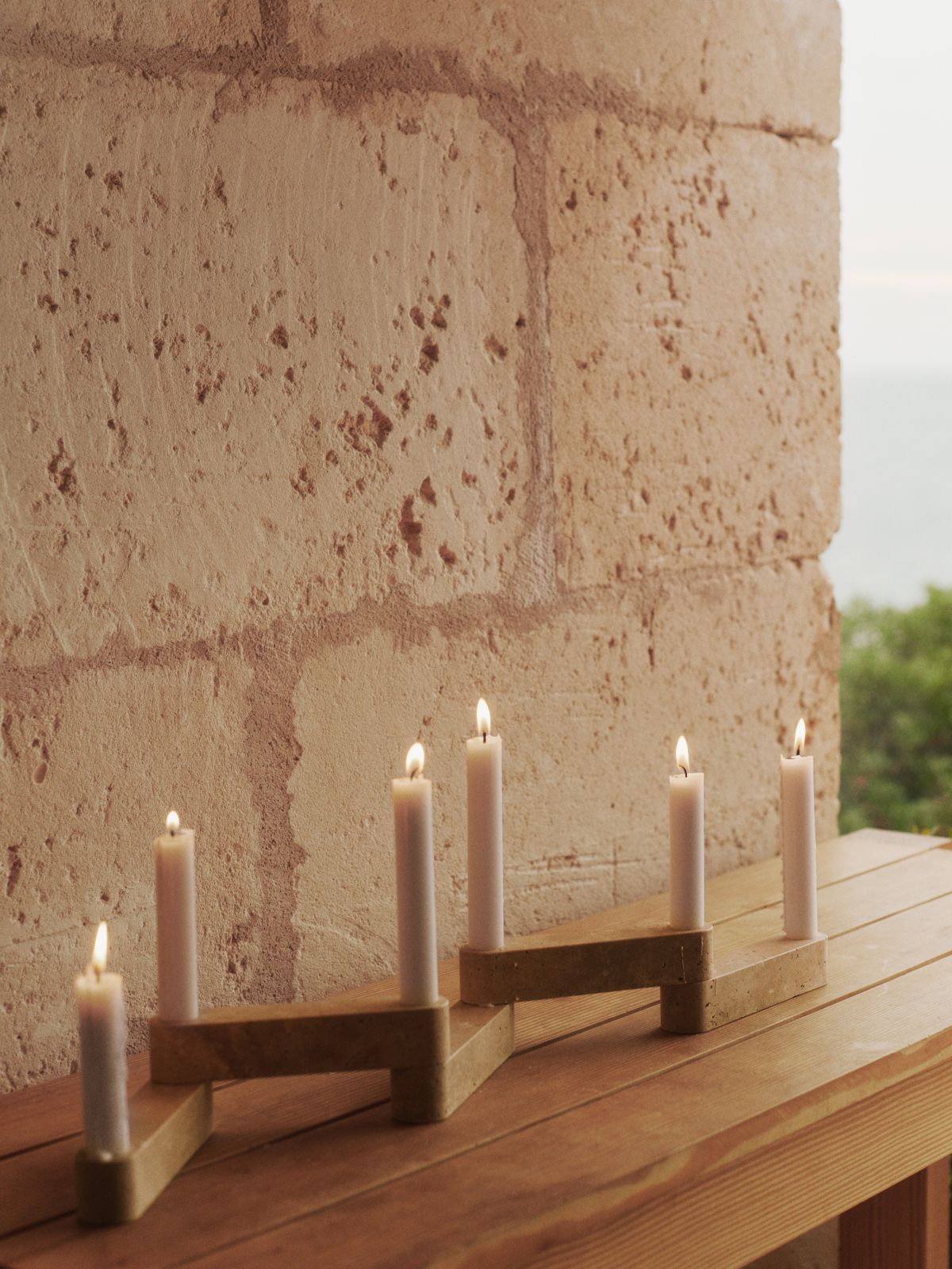 Newel Modular Kerzenhalter von Ferm Living mit fünf brennenden Kerzen auf einem Holztisch.