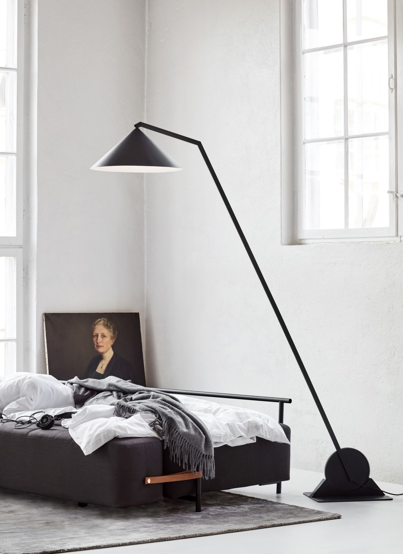 Schwarze Gear Floor Stehleuchte von Northern neben einem Bett in einem hellen Raum.