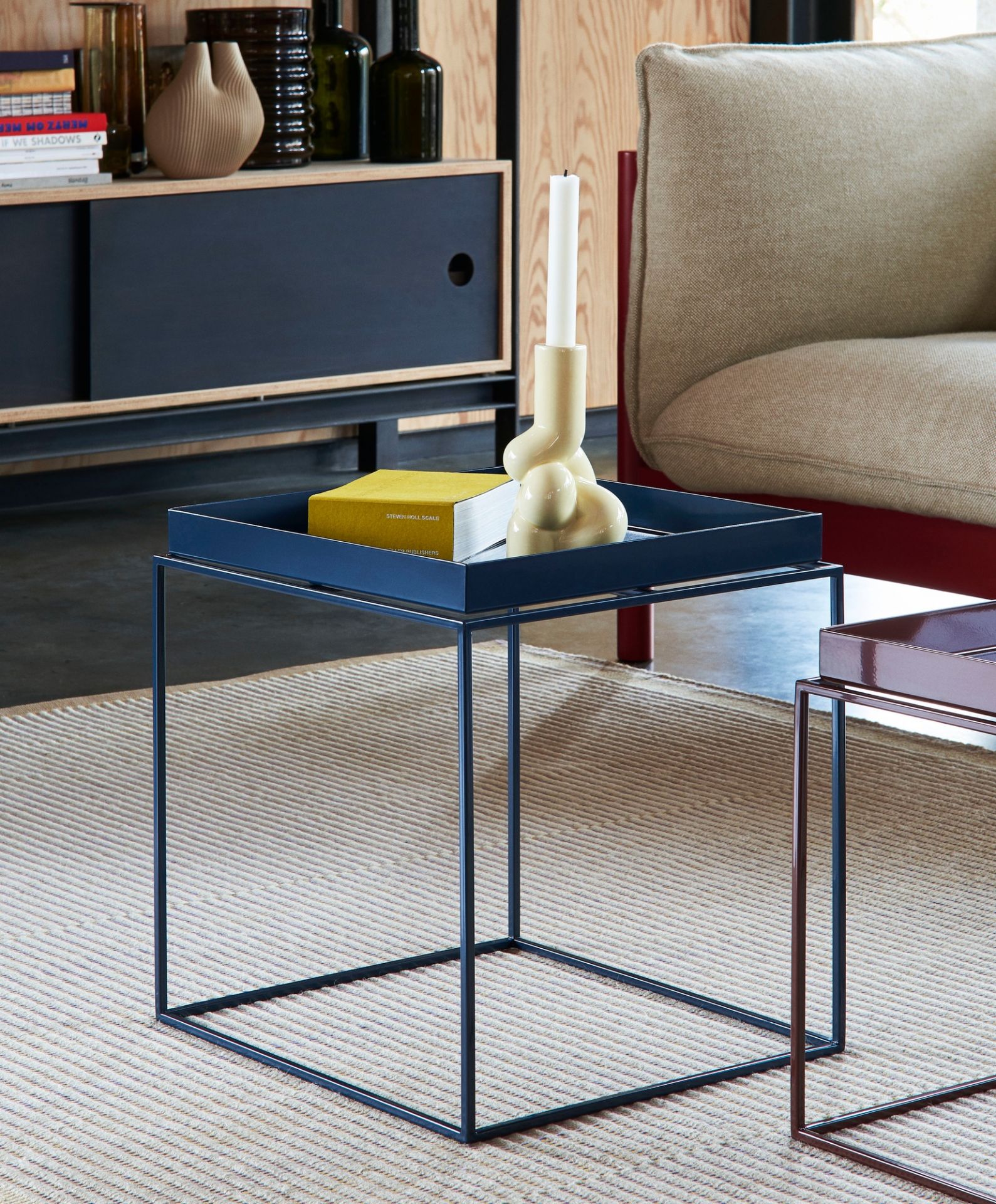 Detailaufnahme des Tapis Teppich Hay, kombiniert mit einem blauen Couchtisch, Buch und Kerzenständer.