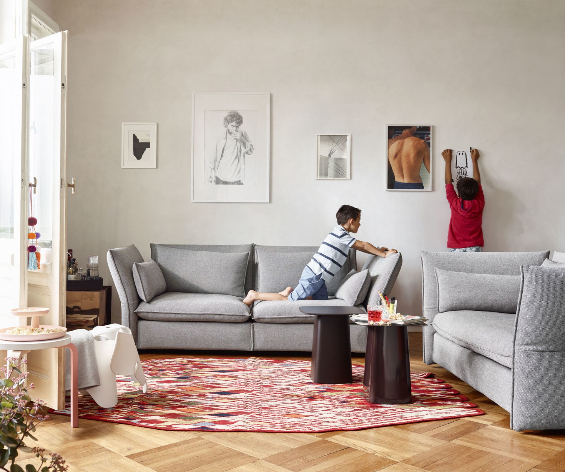 Wohnzimmer mit grauem Sofa, Teppich und zwei Metal Side Table Beistelltischen von Vitra in dunklem Braun.