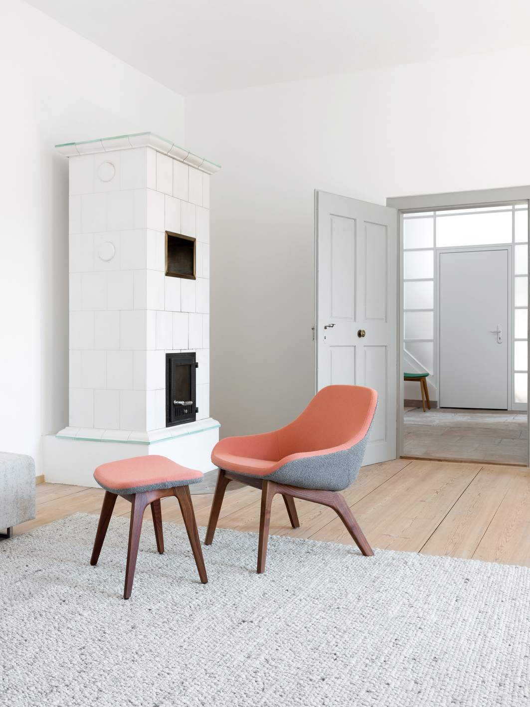 Morph Lounge Chair Sessel mit Fußhocker in modernem Wohnzimmer mit Kamin und Holzboden.