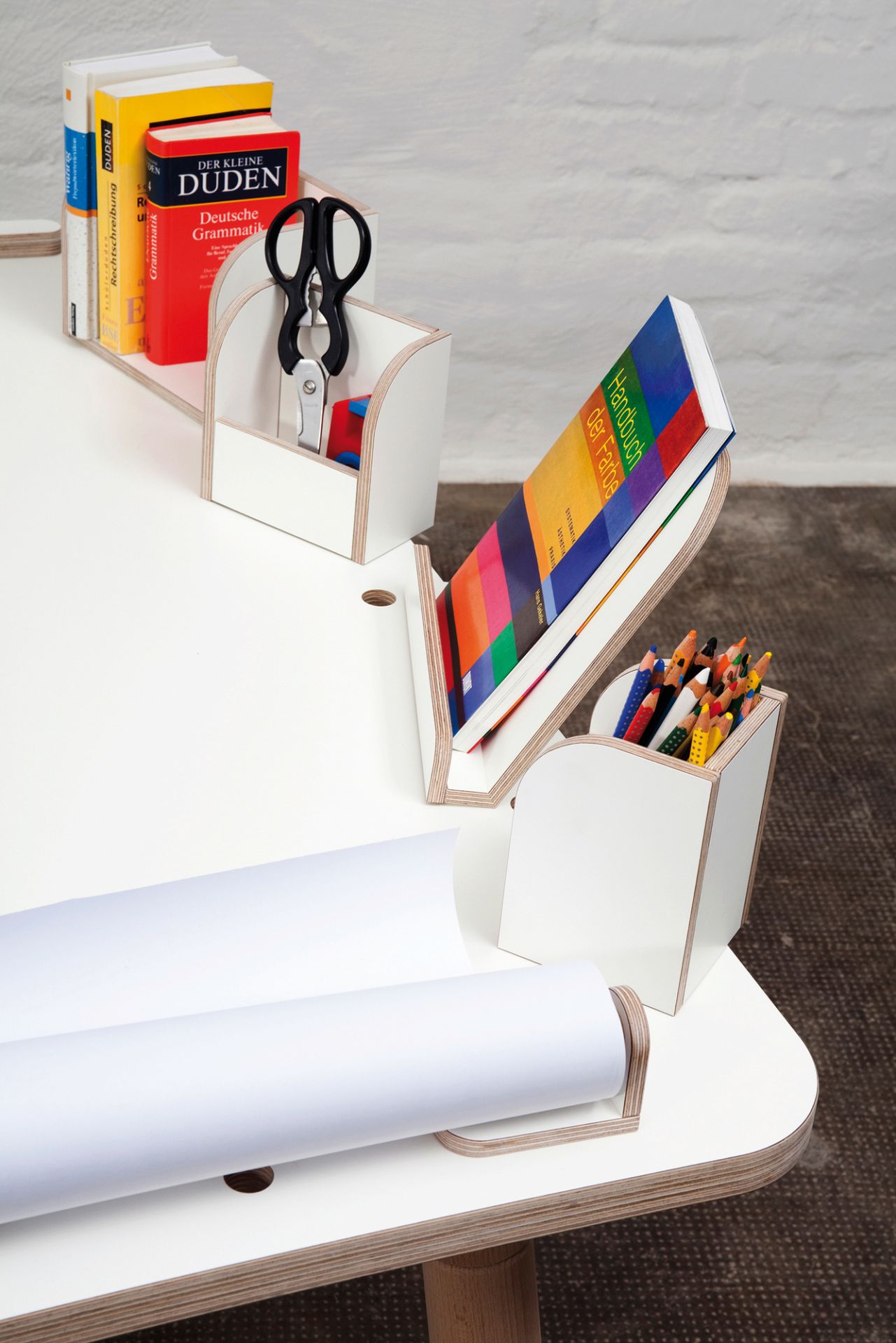 Growing Table 9-teiliges Set: Detailansicht des weißen Kinderschreibtischs mit Stiften, Papierrolle und Lernmaterialien.