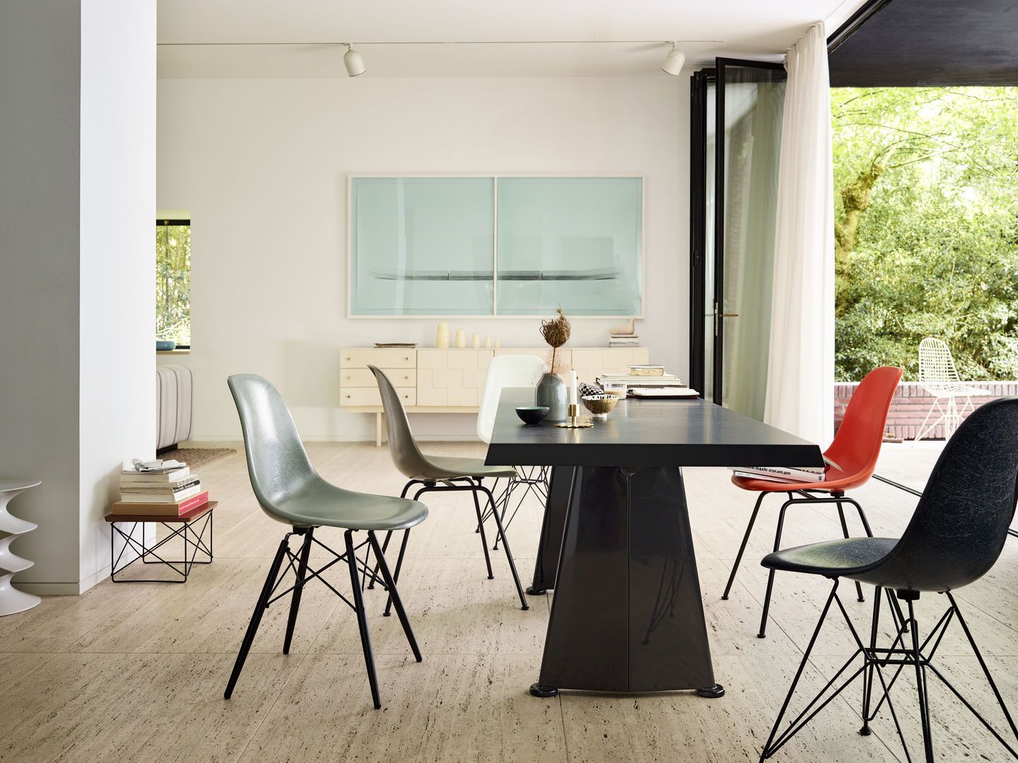 Esszimmer mit Esstisch und mehreren bunten Eames Fiberglass Stühlen DSW von Vitra mit Sitzpolster.