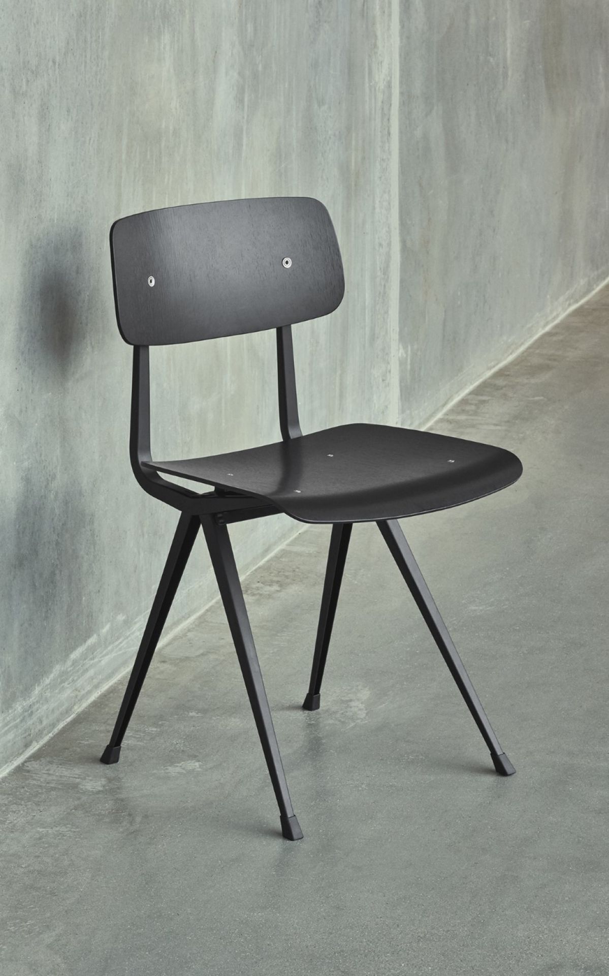 Schwarzer Result Chair Stuhl von Hay mit Holz-Sitzfläche und filigranem Stahlgestell vor einer grauen Wand.