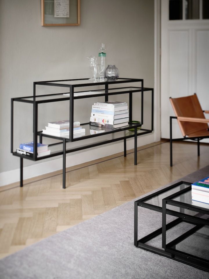 Modernes schwarzes Regal mit Glasböden, dekoriert mit Büchern und Glasobjekten, im Wohnzimmer.