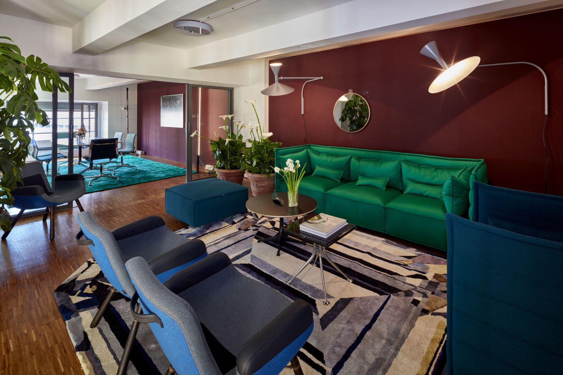 Wohnzimmer mit zwei blauen East River Chair Sesseln von Vitra und grüner Couch.