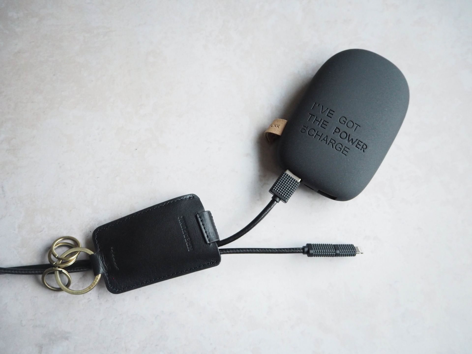 cCHAIN Schlüsselanhänger von Kreafunk mit USB-Kabel, schwarzes Lederetui und goldene Schlüsselringe auf hellem Untergrund.