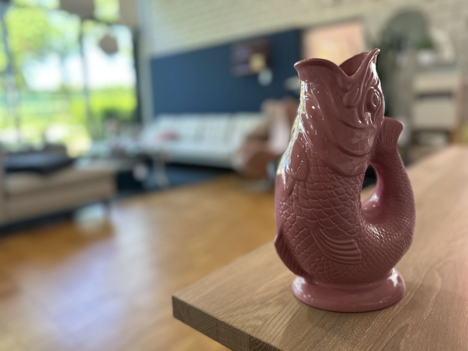 Rosa Gluckigluck Fischkaraffe auf einem Holztisch. Dekorative Wasserkaraffe oder Blumenvase in Fischform.