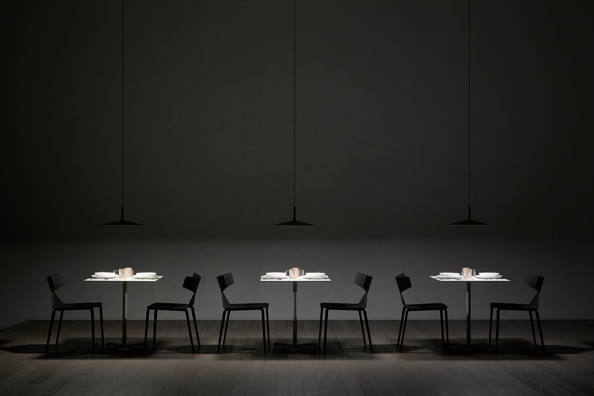 Aplomb LED Pendelleuchten von Foscarini über Esstischen mit Gedeck in dunklem Ambiente.