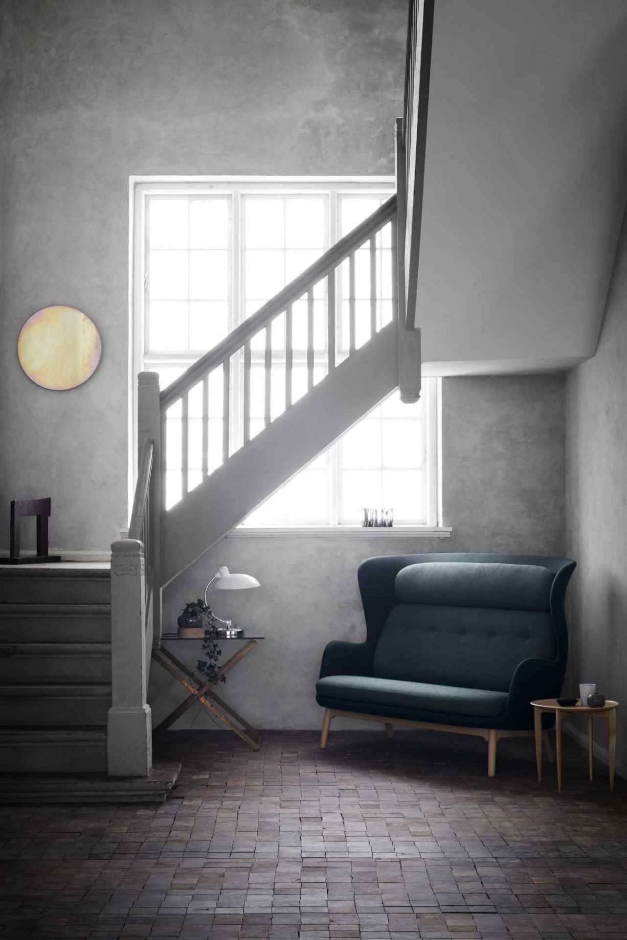 Elegantes, dunkelblaues Ro 2-Sitzer Sofa von Fritz Hansen im skandinavischen Design neben einer Treppe.