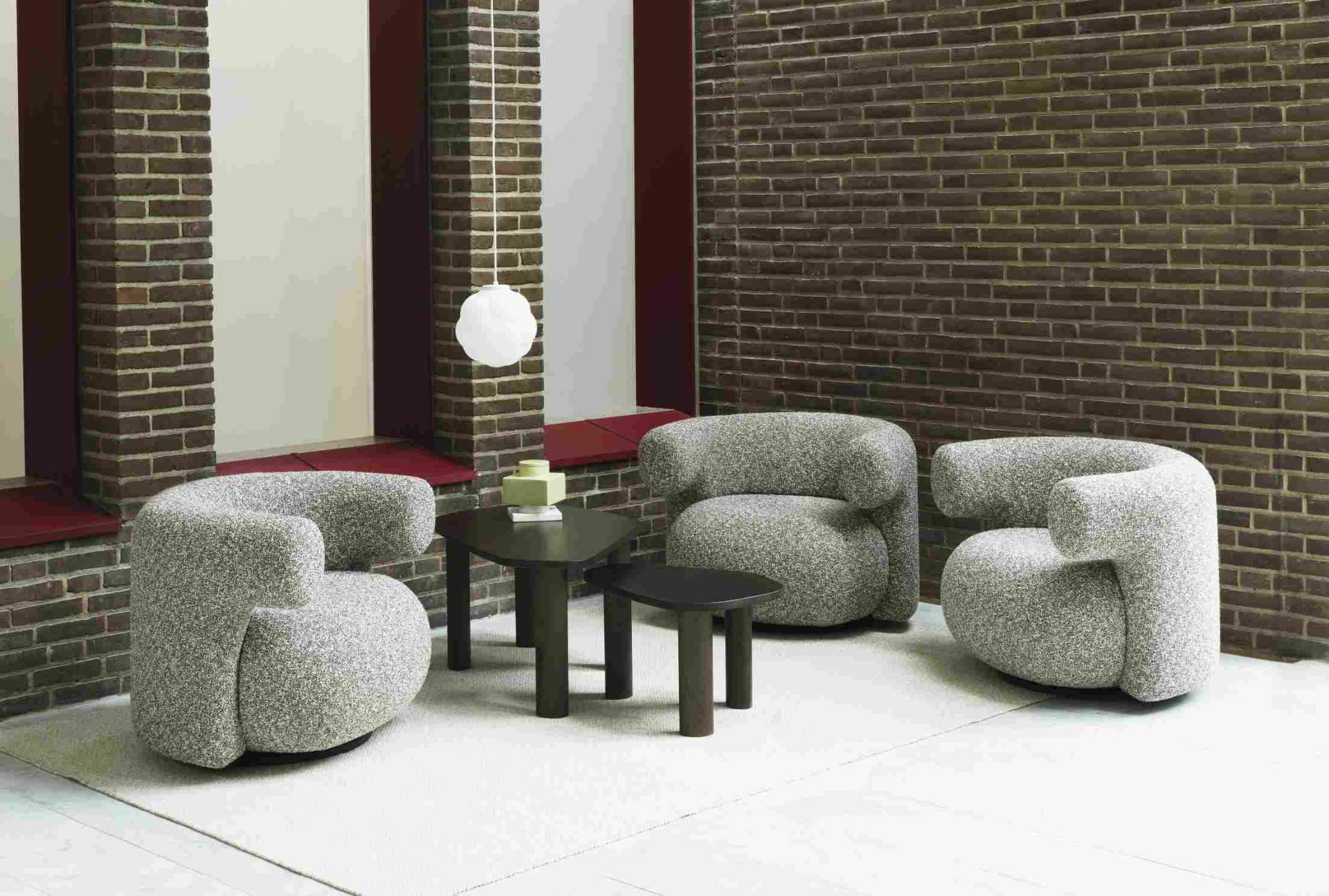 Weiße Bubba Pendelleuchte von Normann Copenhagen über Lounge-Bereich mit Sesseln und Tischen.