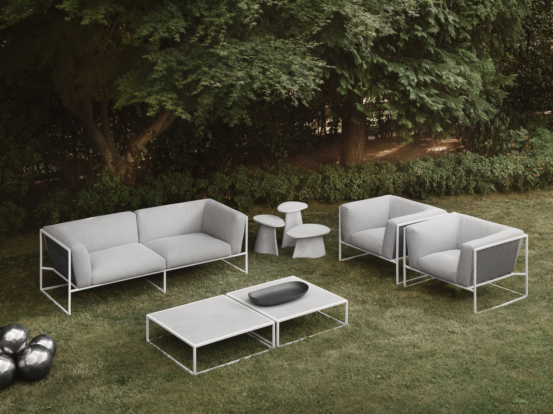 MDF Italia Fossil Beistelltisch im Garten mit Sofa, Sesseln und Couchtisch in Grau.