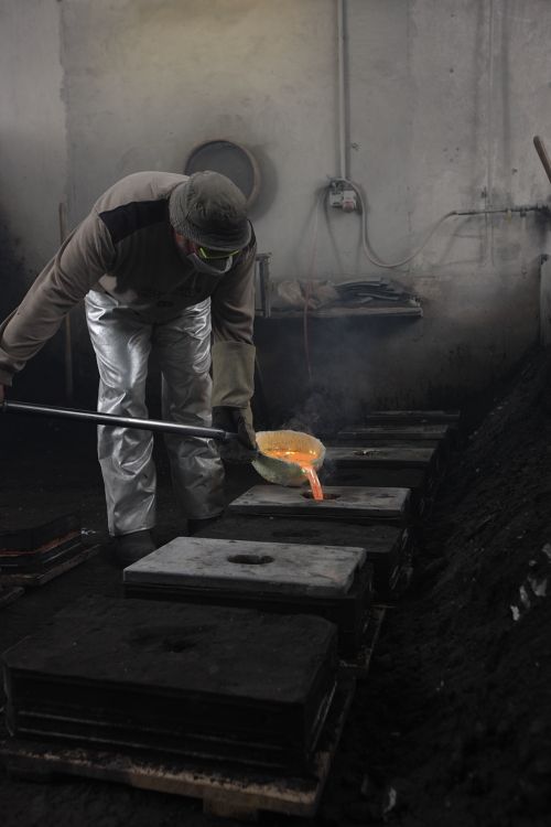 Gießen von flüssigem Metall in Formen zur Herstellung von Türdrückern im Art Déco Stil.