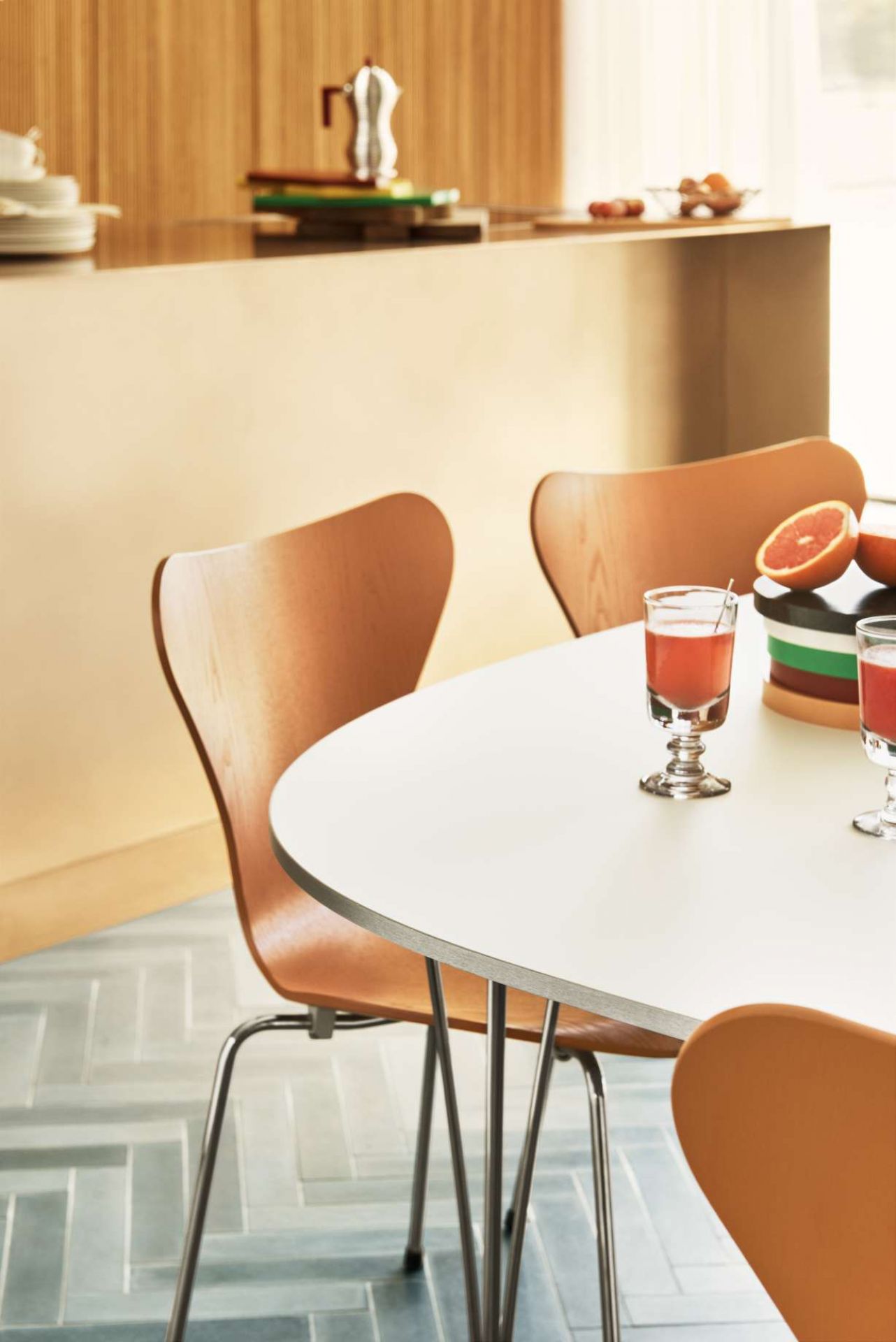 Nahaufnahme von Fritz Hansen Siebener Stühlen mit hellem Holzfurnier und verchromten Beinen an Esstisch.