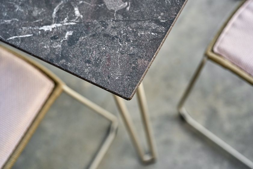 Detailaufnahme der Tischplatte vom Weishäupl Slope Tisch, ein Outdoor Esstisch mit Marmoroptik und Stühlen.