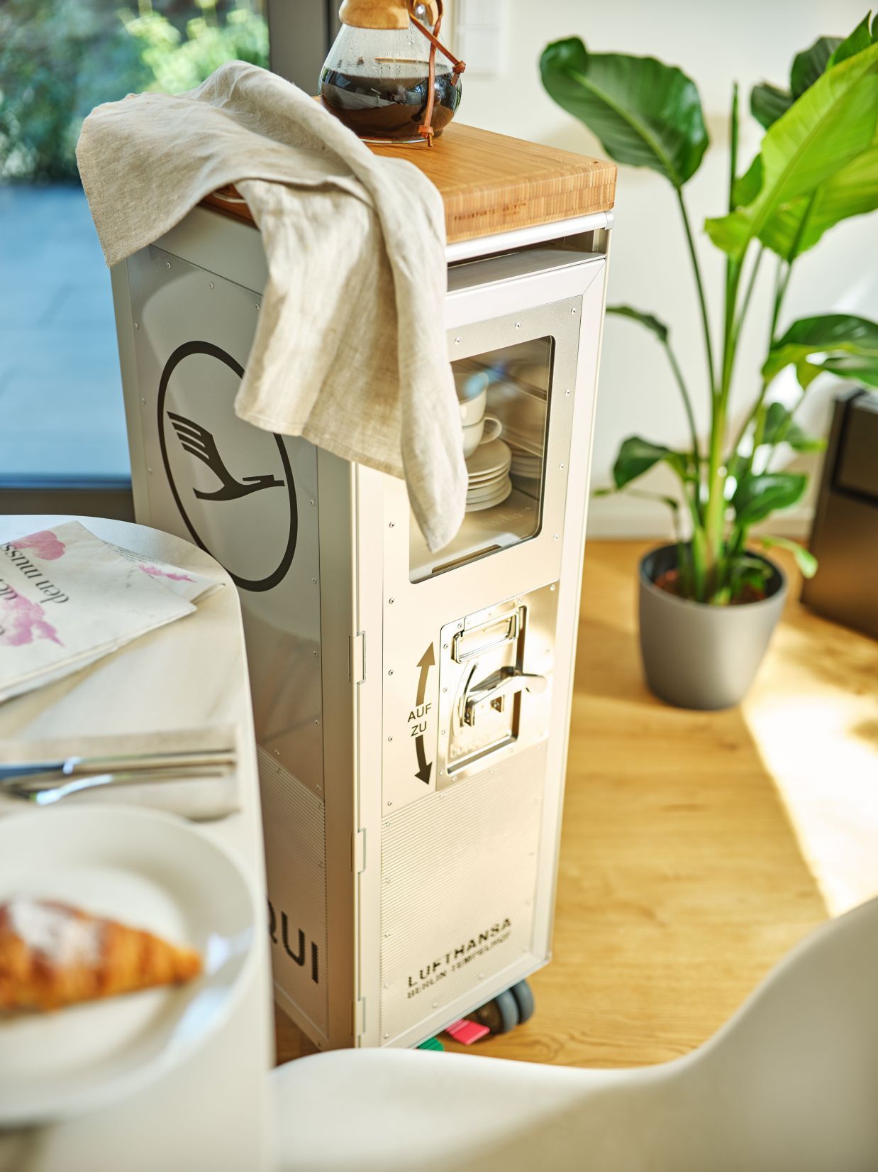 Lufthansa Ju 52 Flugzeugtrolley Bordbar im Interieur mit Geschirr, Kaffeebereiter und Handtuch auf Bambusplatte.