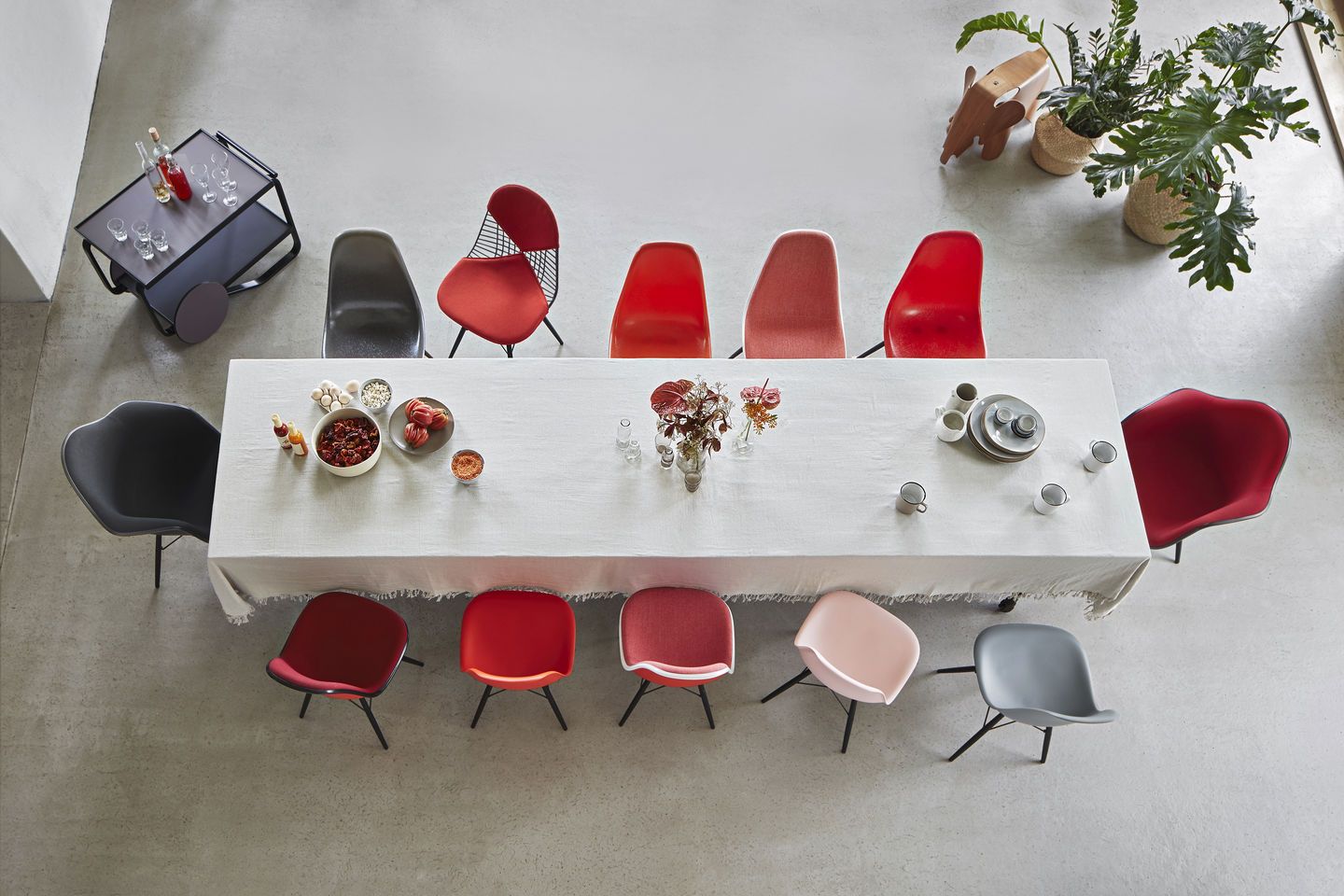 Vogelperspektive auf Esstisch mit Vitra DKW-5 Wire Chairs und Kunststoffstühlen in verschiedenen Farben.