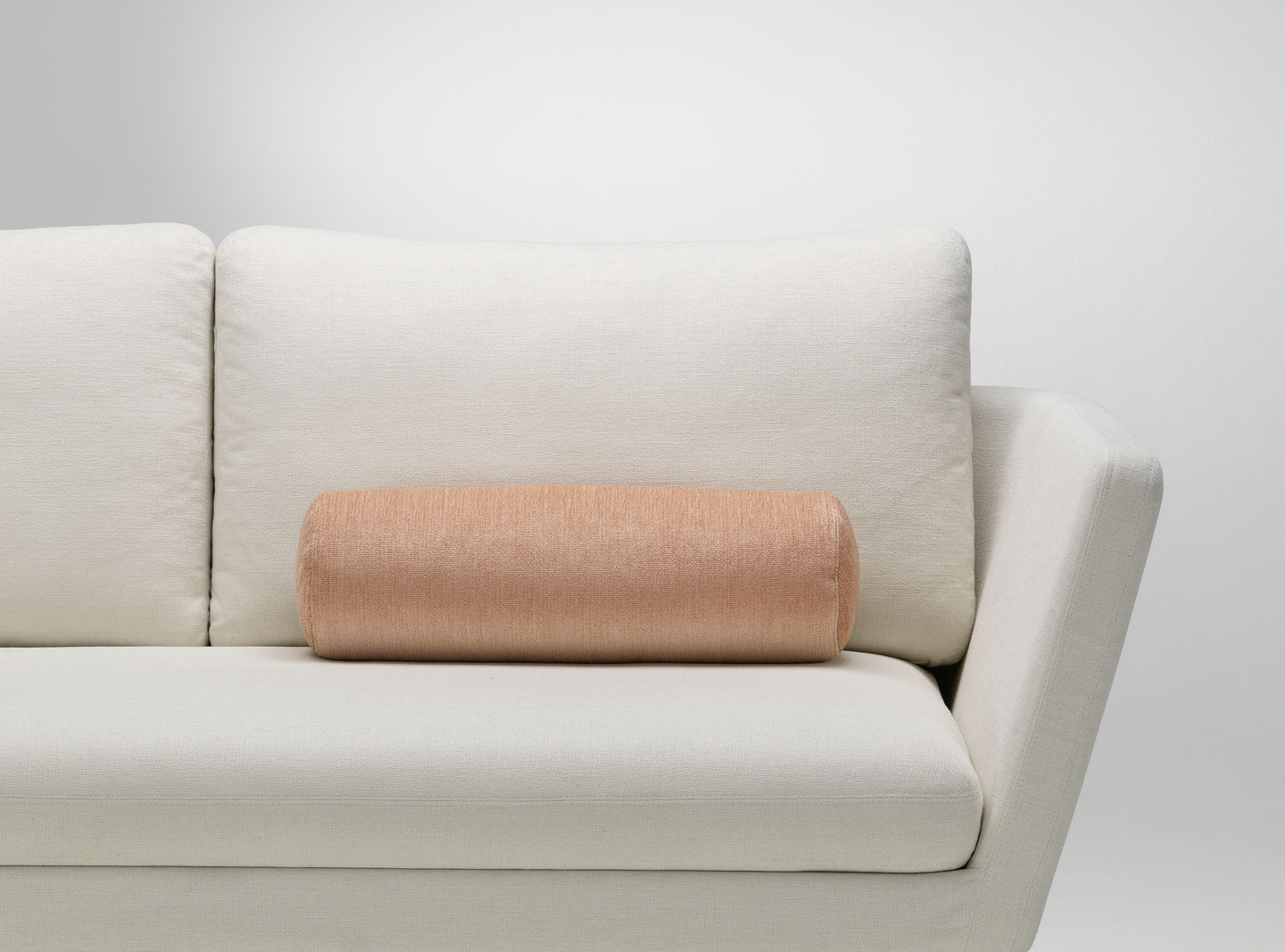 Vitra Kissen: Zylindrisches Sofakissen in Apricot auf einem weißen Sofa, modernes Wohnaccessoire für stilvolles Ambiente.