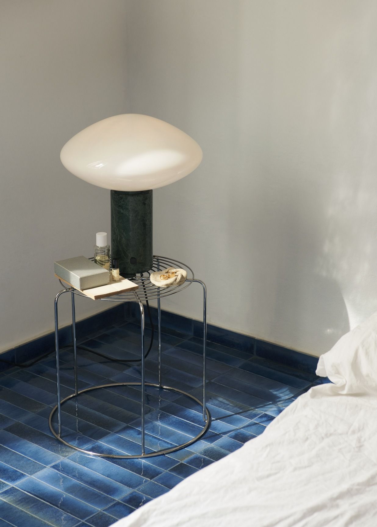 AndTradition Wire Stool VP11 als Beistelltisch im Schlafzimmer mit Lampe und Accessoires.