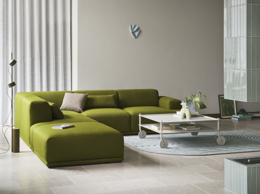 Wohnzimmer mit grünem Sofa und Muuto Flow Coffee Table Couchtisch auf Rollen.