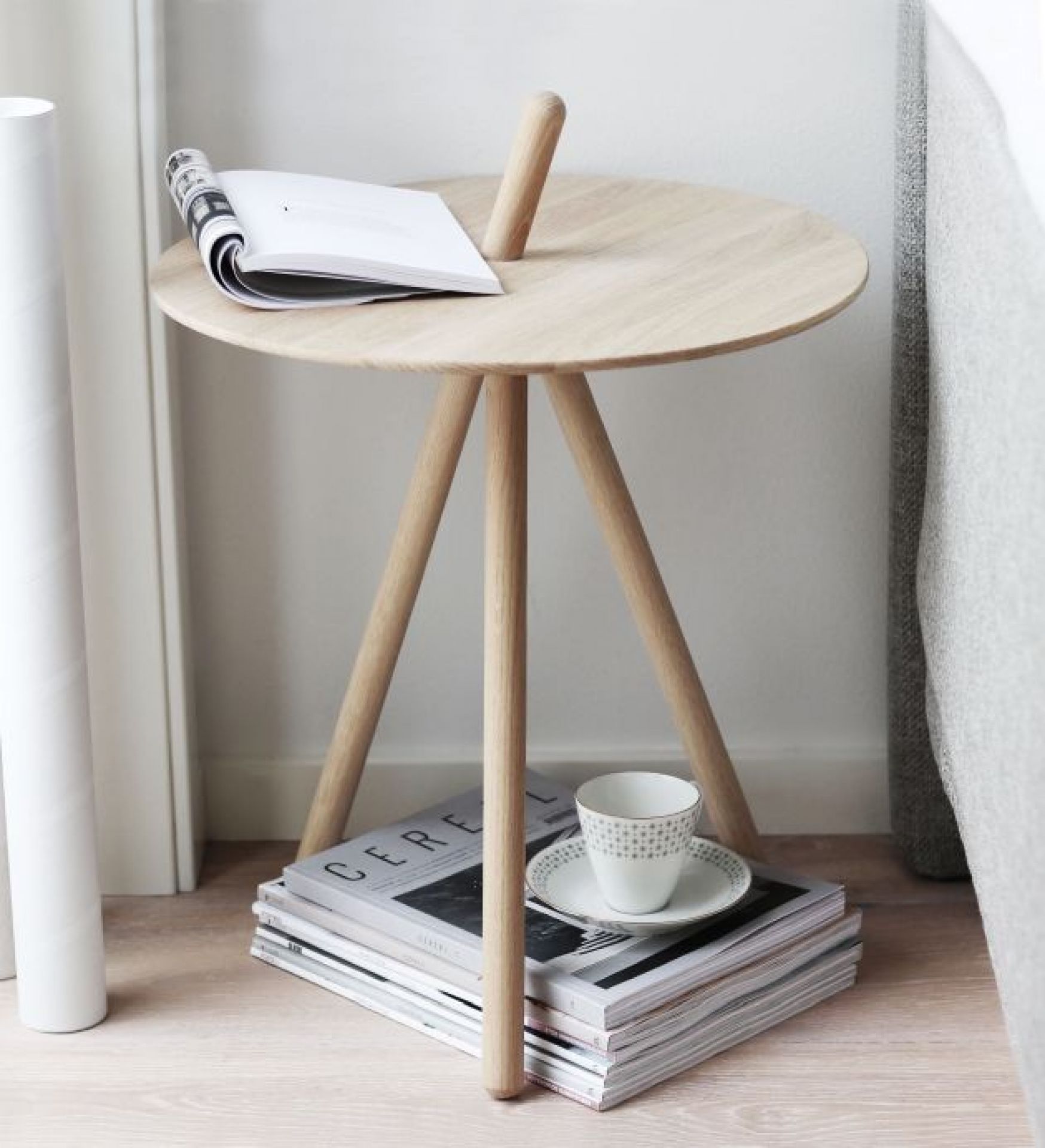 Come Here Beistelltisch von Woud aus hellem Holz mit Magazinen und Teetasse.