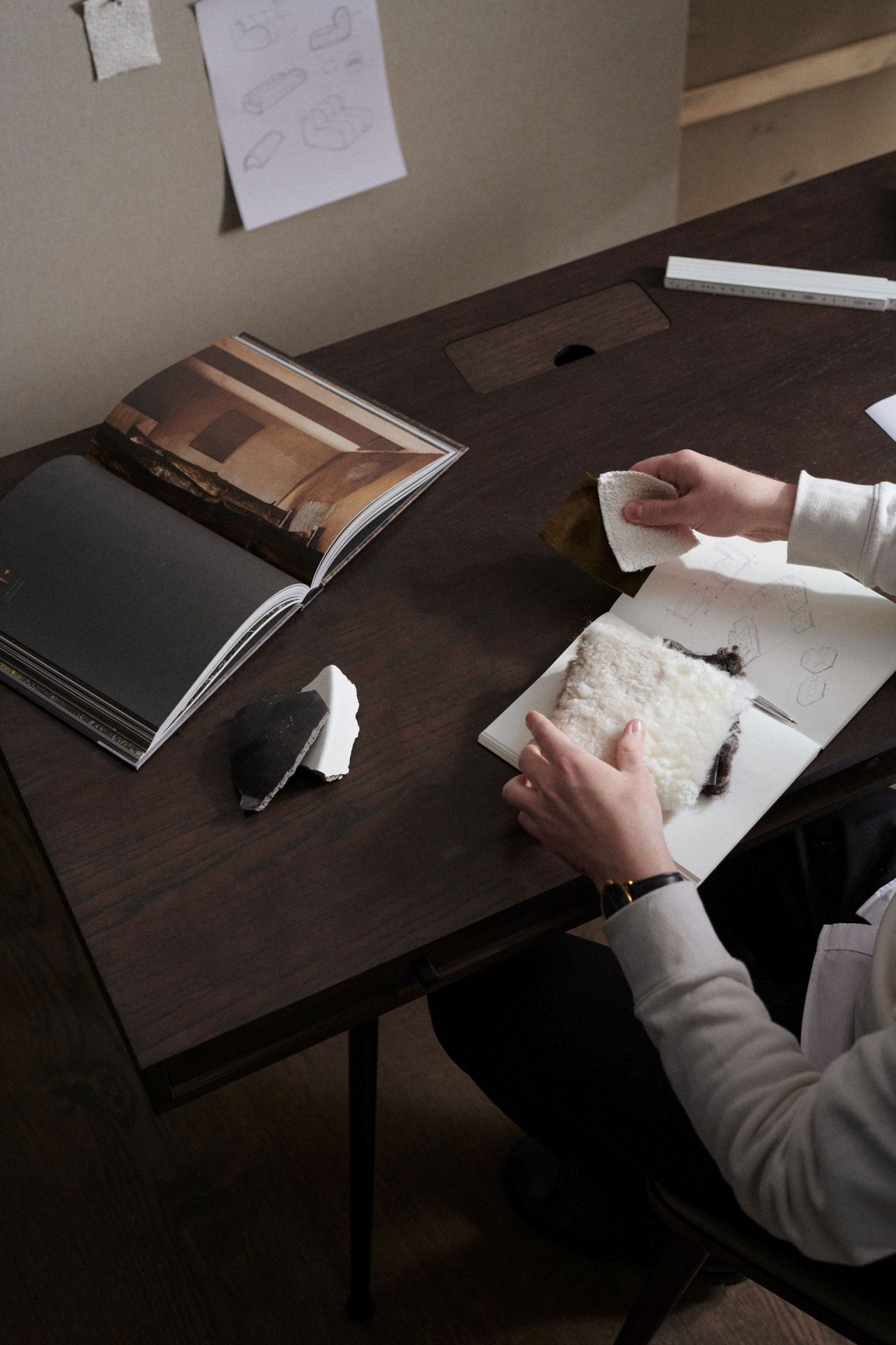 JFK Büroschreibtisch Norr11 mit Standard Beinen aus dunklem Holz, umgeben von Designelementen und Stoffmustern.