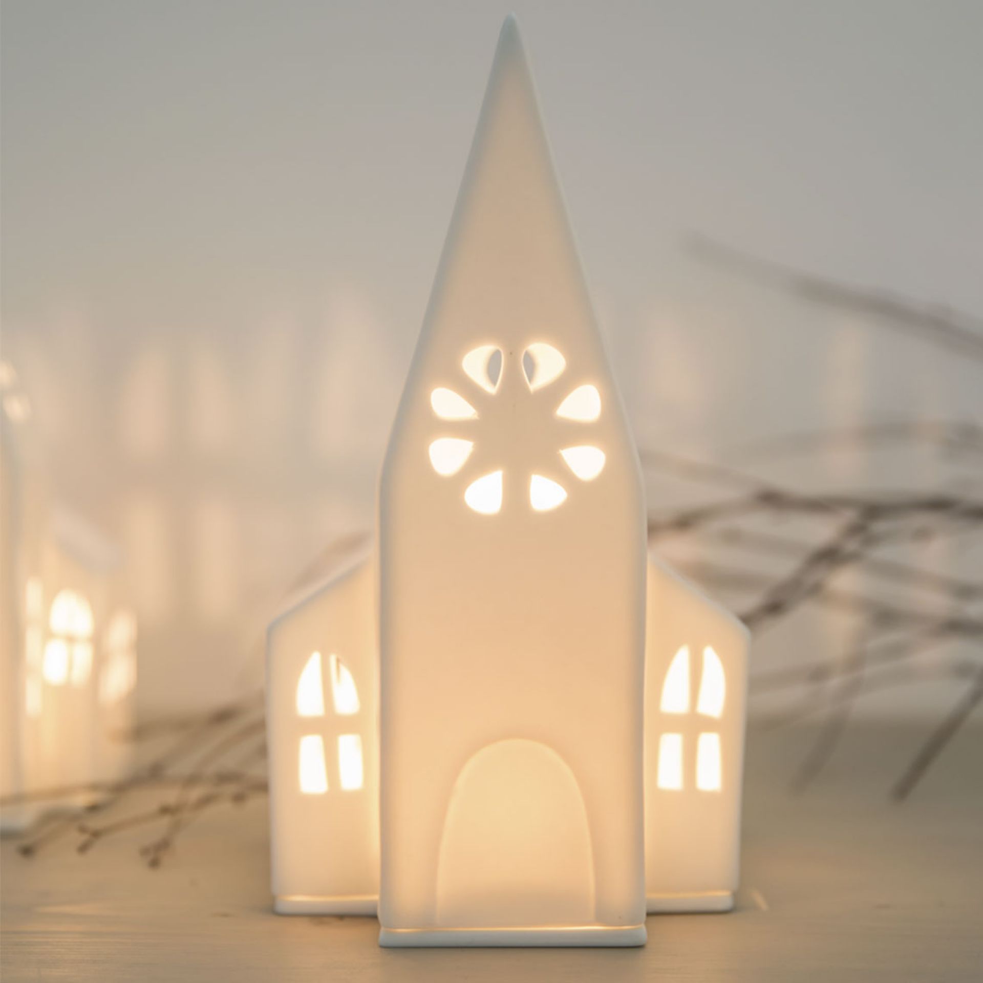 Detailaufnahme des Zuhause Lichthaus Kirche Räder, eine leuchtende, weiße Keramik Kirche als stimmungsvolle Weihnachtsdekoration.