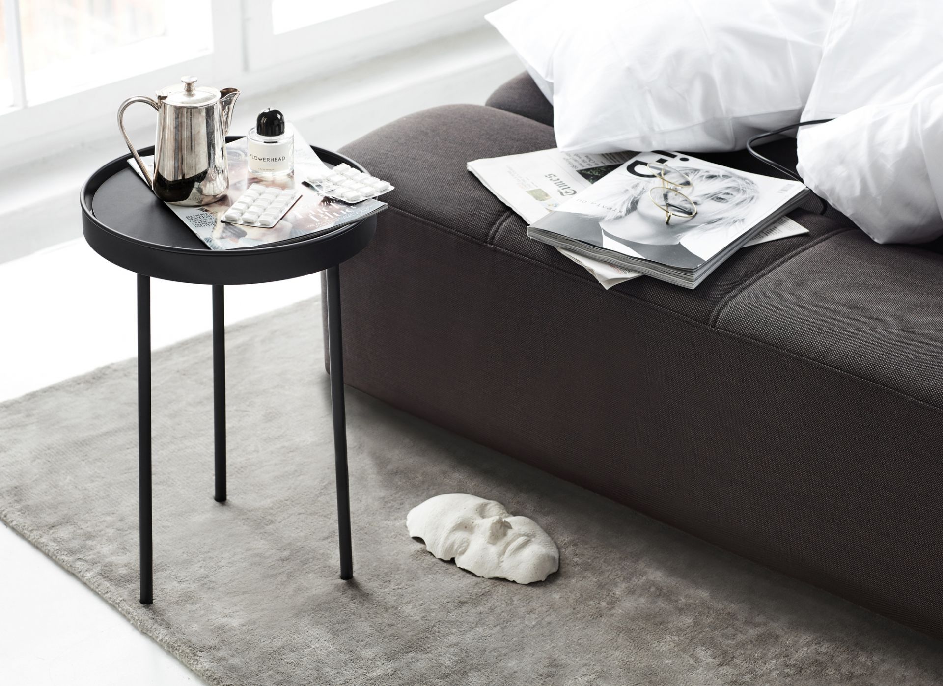 Graues Daybe Schlafsofa mit Kissen, Beistelltisch, Teekanne und Dekoration in modernem Wohnzimmer.