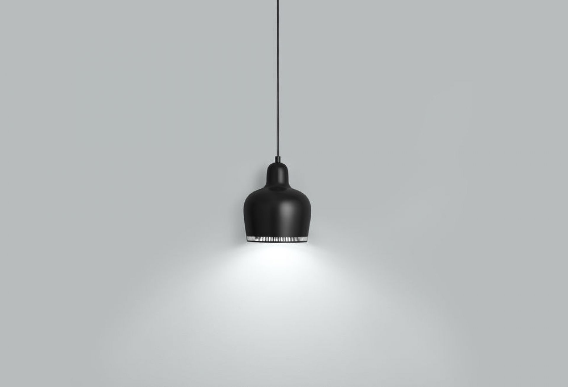Schwarze A330S Pendelleuchte von Artek mit warmem Lichtkegel vor grauem Hintergrund. Design Lampe.