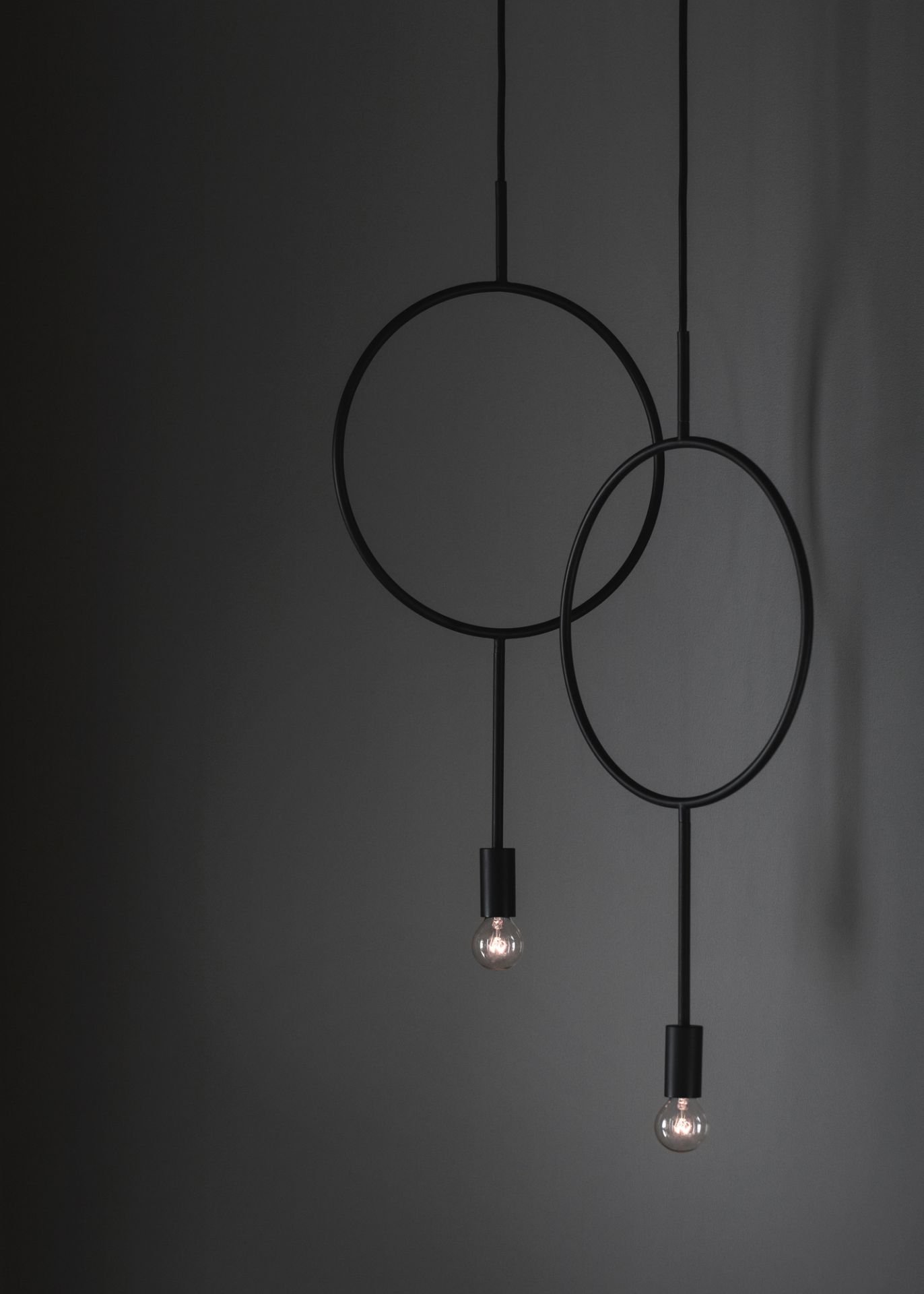 Schwarze Circle Pendelleuchte mit zwei Kreisen und Glühbirnen vor dunklem Hintergrund. Moderne Hängelampe.