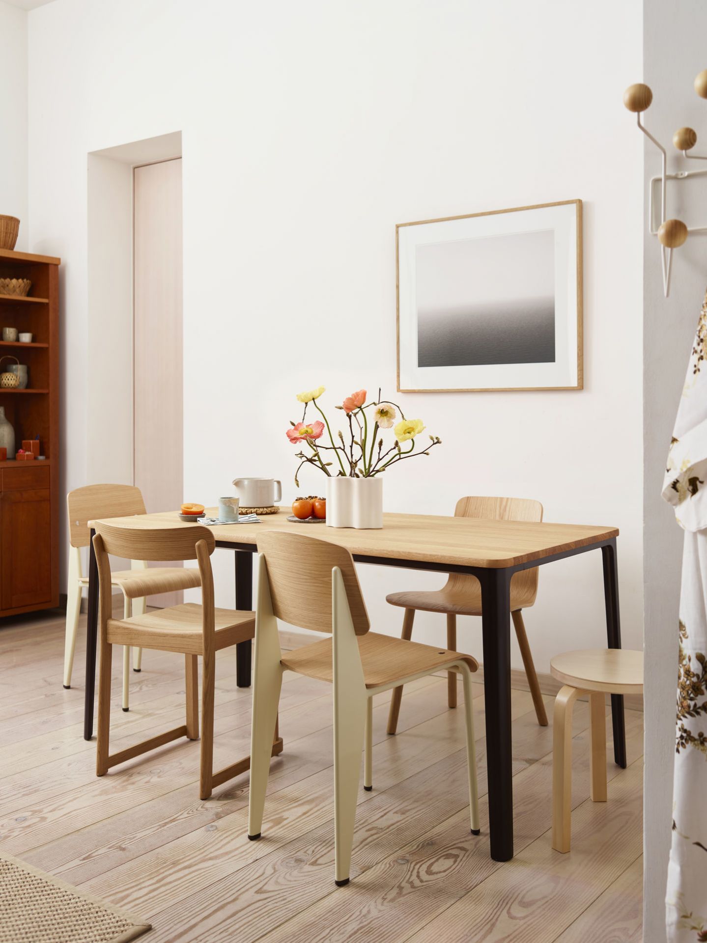 Esszimmer mit Holztisch, Blumen und vier Vitra Stühlen Standard in hellem Holz und Metall.