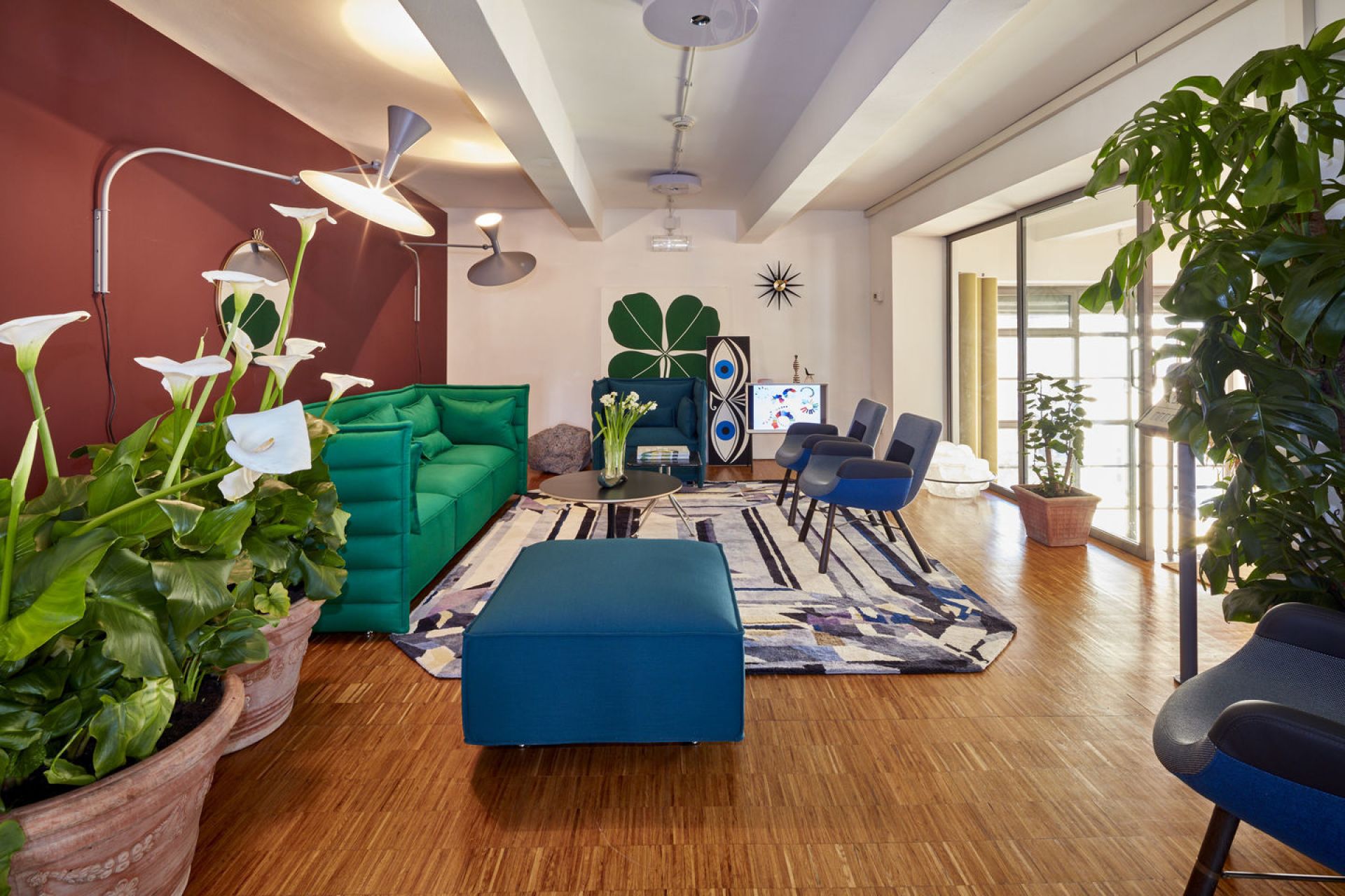 Wohnzimmer mit East River Chair Sessel von Vitra in blau, grünes Sofa und modernen Möbeln.