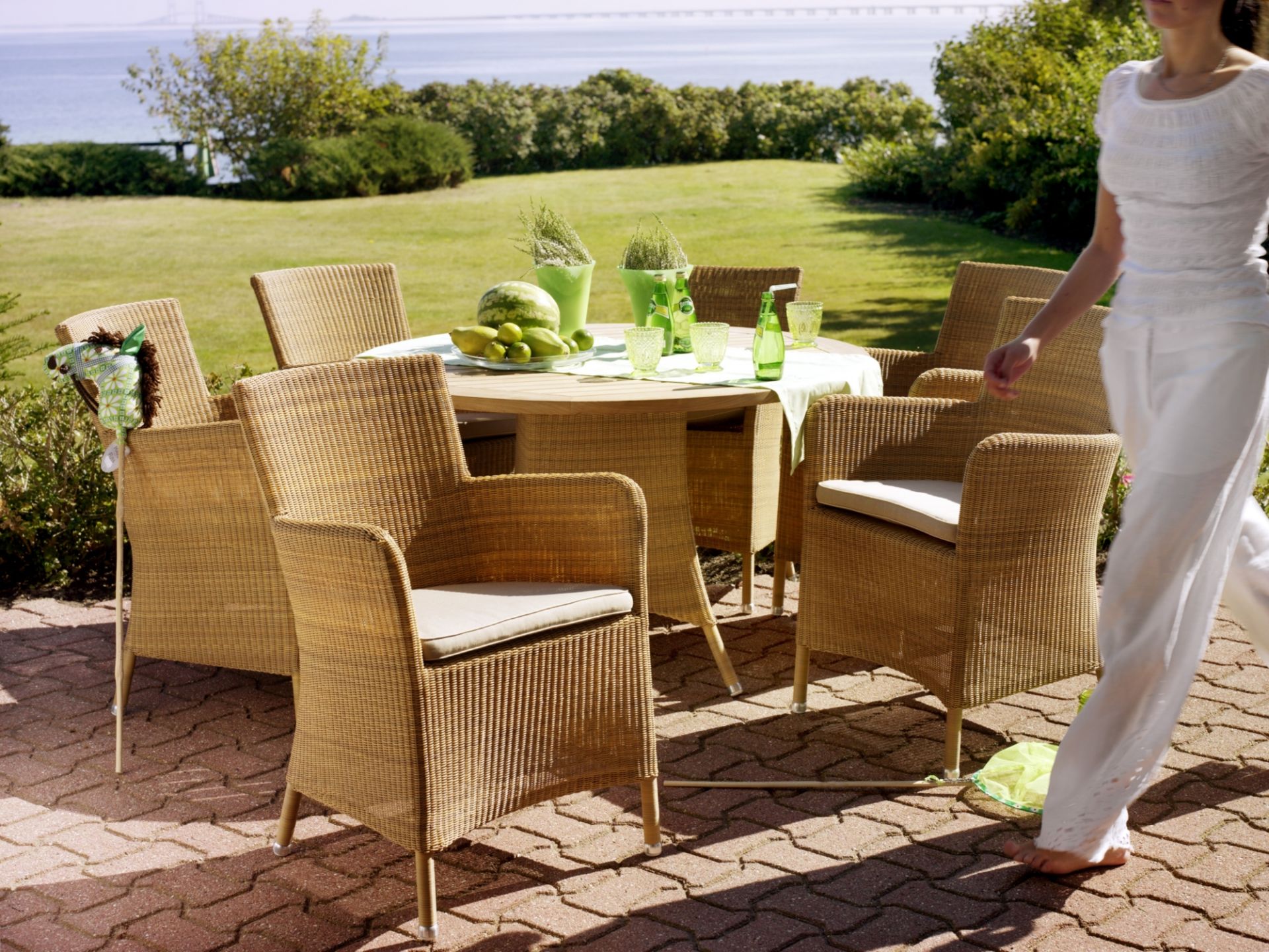 Hampsted Outdoor Sessel von Cane-Line aus Rattan um einen Gartentisch auf der Terrasse.