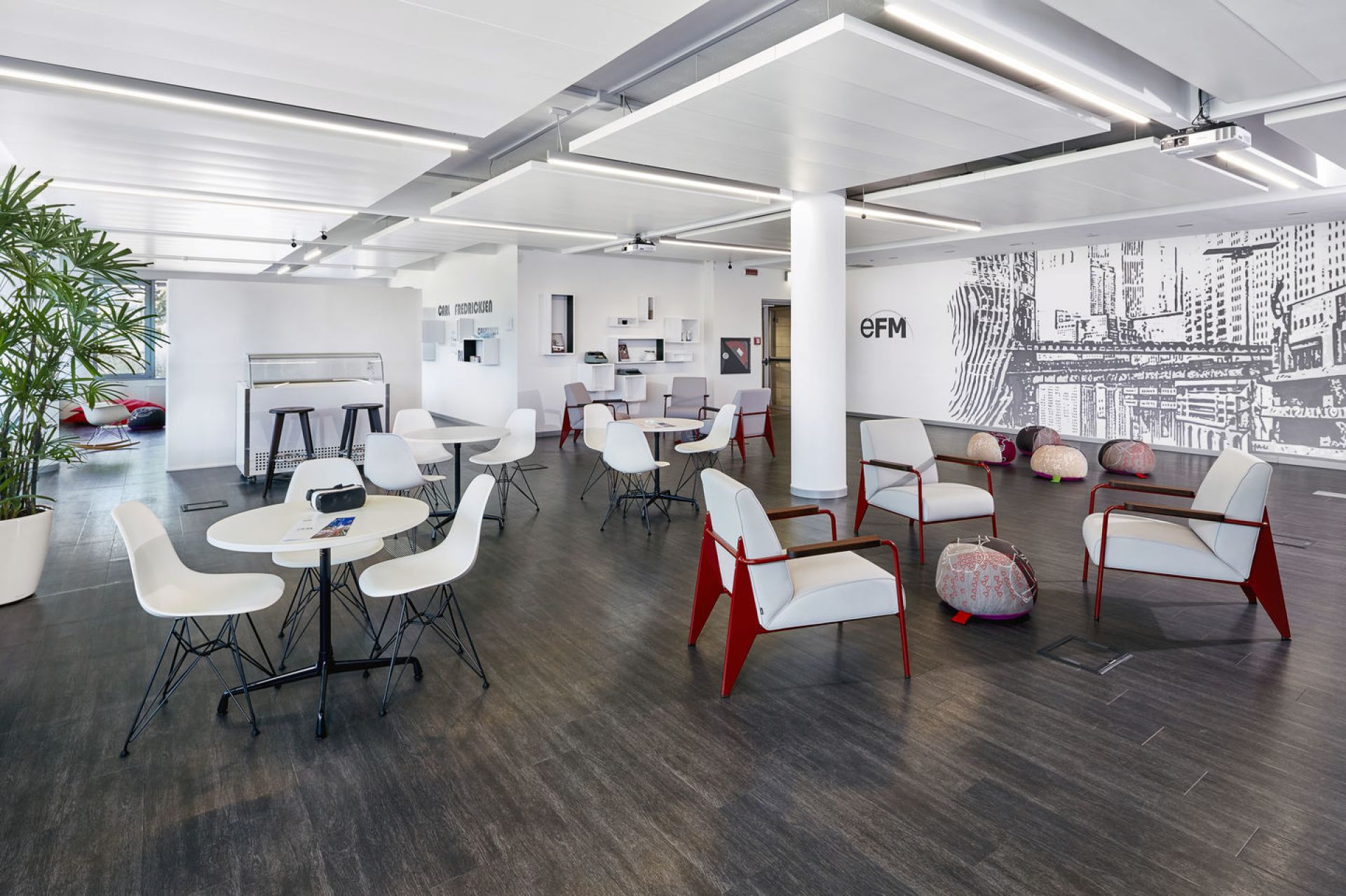 Heller Büroraum mit mehreren Vitra Fauteuil De Salon Sesseln mit roten Armlehnen und weißen Sitzflächen.