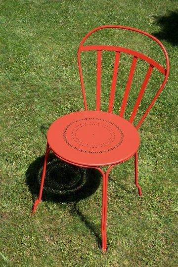 Roter Louvre Stuhl von Fermob für den Außenbereich auf Rasen, Gartenmöbel aus Metall.