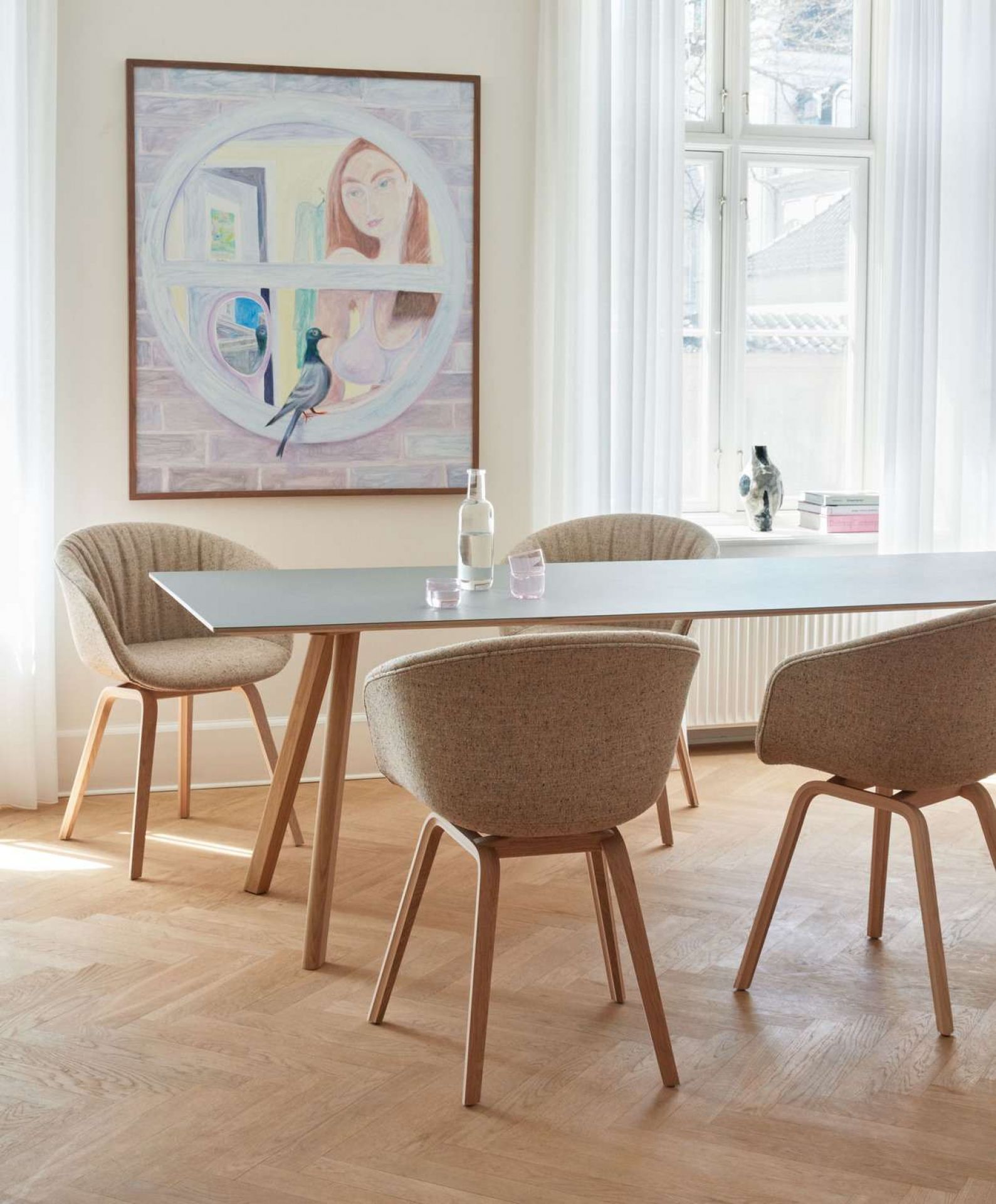 Esszimmer mit vier "About a Chair AAC23" Stühlen mit Stoffbezug und Holzbeinen.