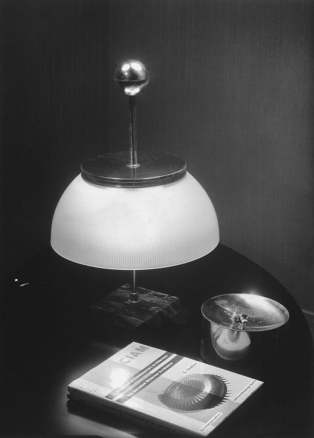 Alfa Tischleuchte von Artemide, klassische Schreibtischlampe mit weißem Schirm und silbernem Fuß auf einem Tisch.