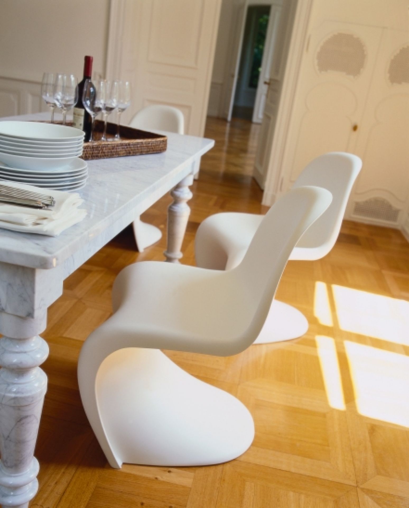 Weißer Panton Chair Kunststoffstuhl von Vitra im Esszimmer mit Marmortisch und Parkettboden.