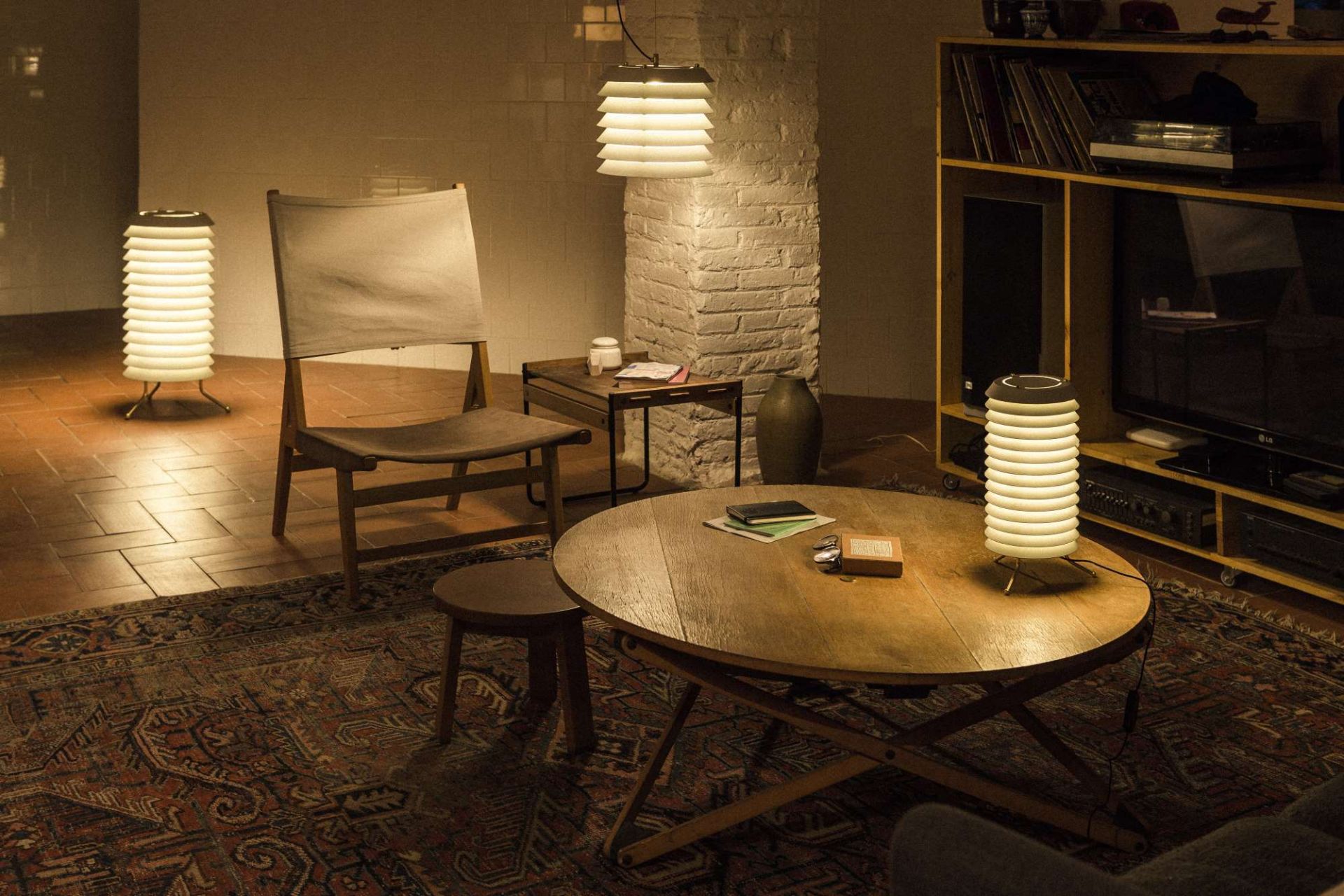 Gemütliches Wohnzimmer mit Santa & Cole Maija Stehleuchte und Pendelleuchte, warmes Licht, stilvolles Design.
