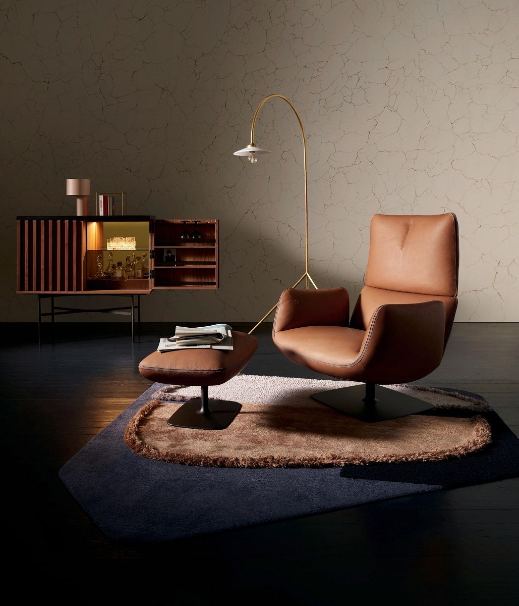 Brauner Jalis Lounge Sessel mit Hocker und Kippmechanik auf Teppich. Gemütliches Wohnzimmer.
