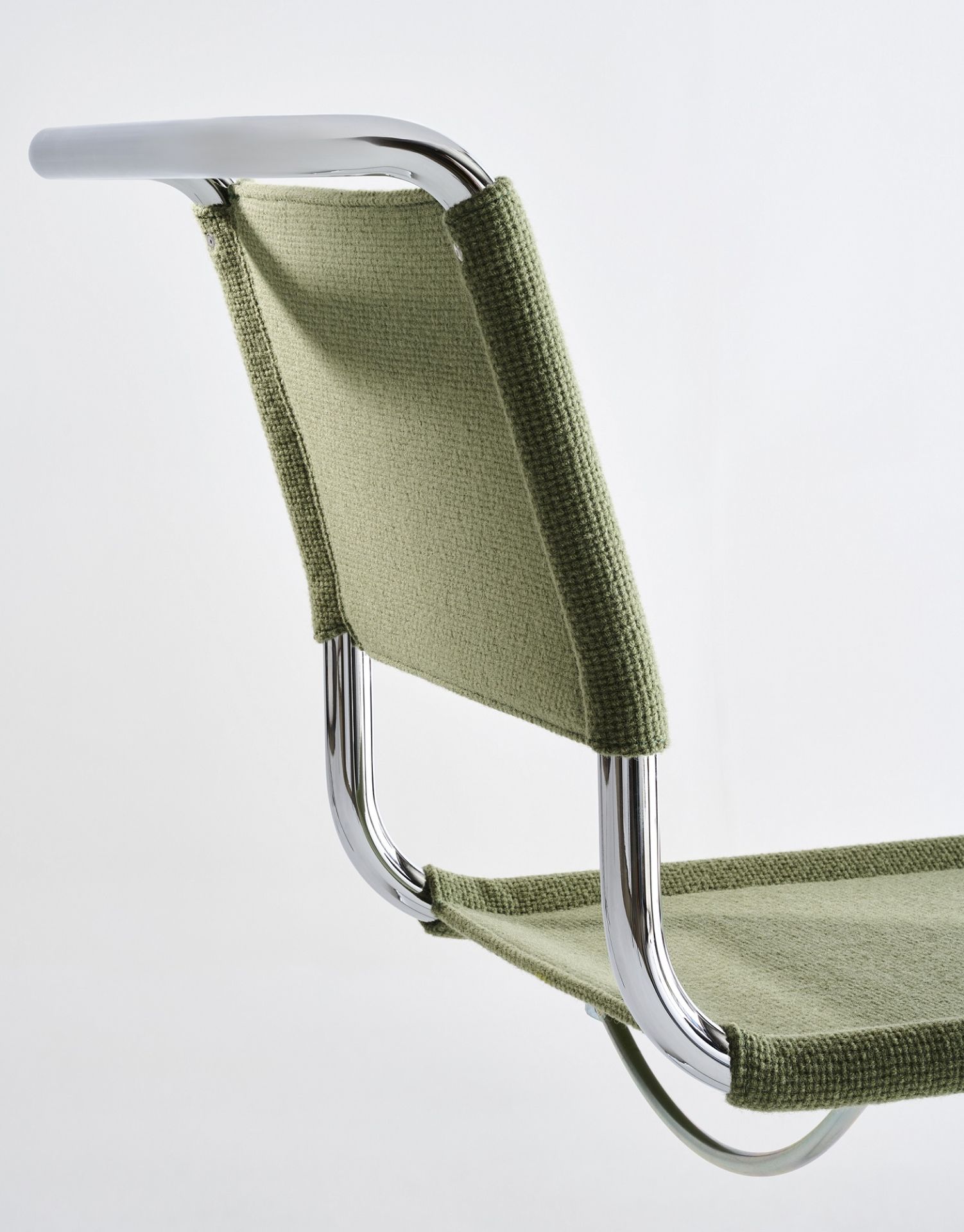 Detailaufnahme des Thonet S 33 V Freischwingers mit grünem Stoffbezug und verchromtem Stahlrohrgestell.