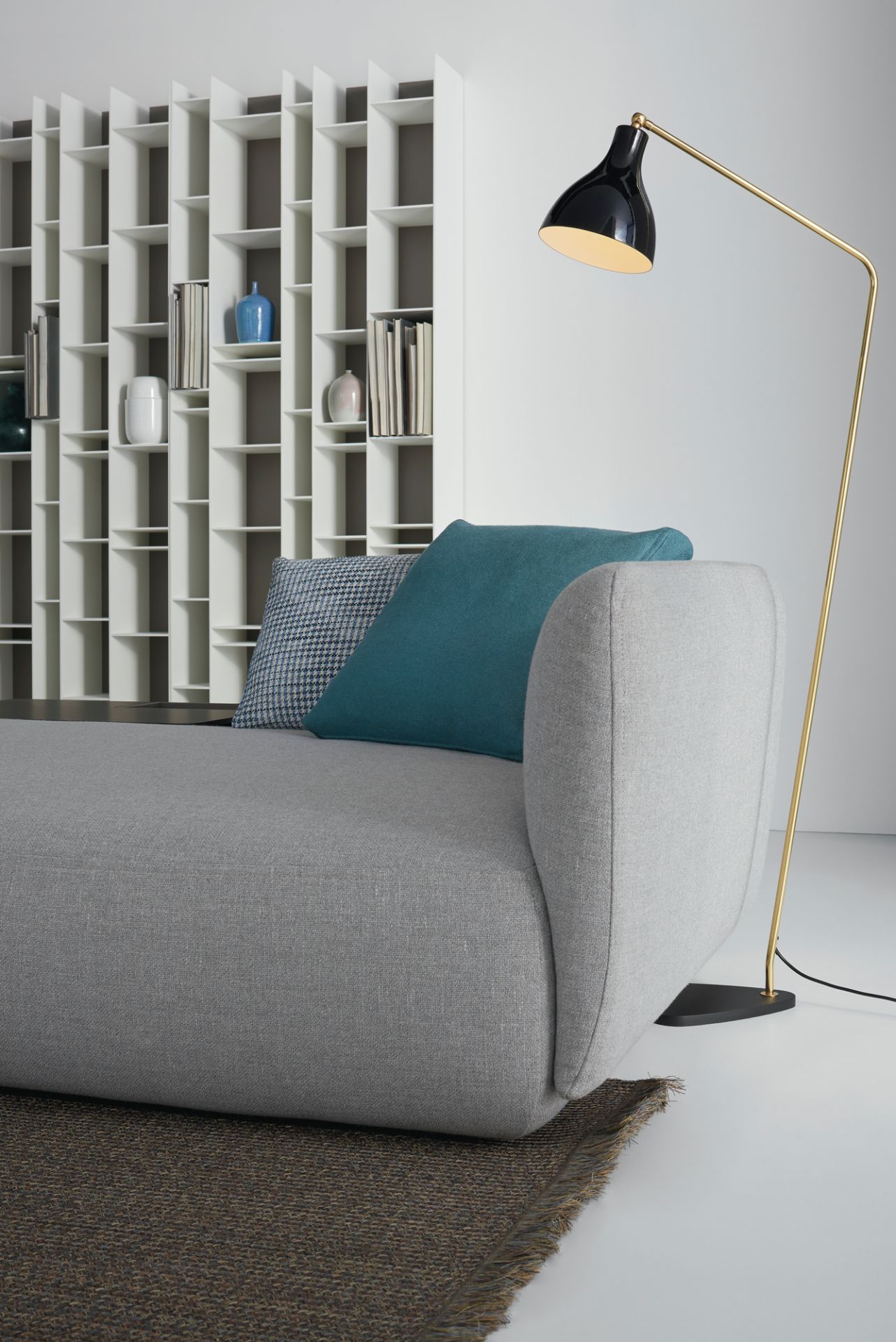 Nahaufnahme des grauen Cosy Sofa von MDF Italia mit Kissen und Stehlampe.