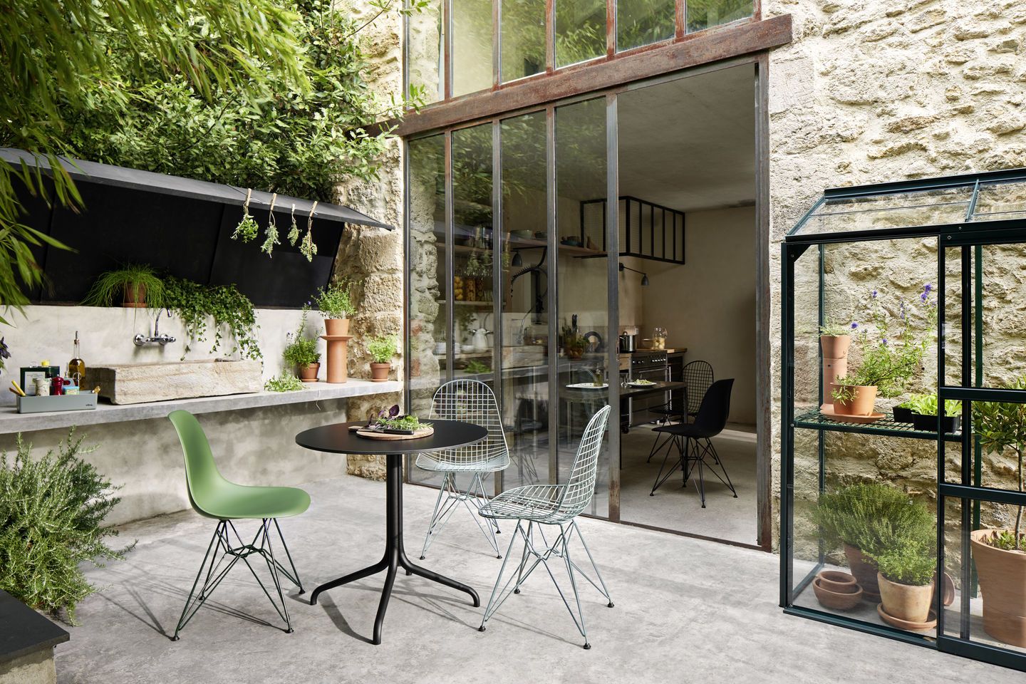Vitra DKR Wire Chair Stuhl ungepolstert im Garten mit Tisch und Pflanzen, modernes Design.
