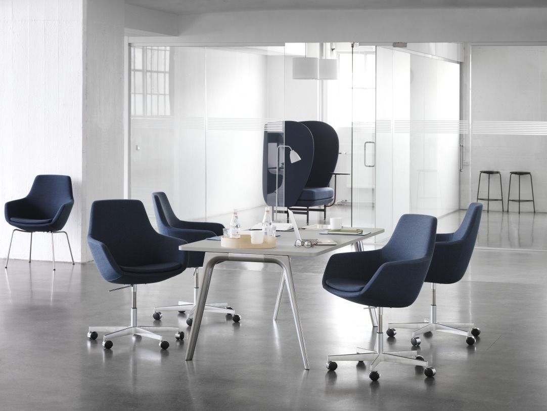Innenraum mit blauen Fritz Hansen Sesseln um einen Tisch, Caravaggio Pendelleuchte im Hintergrund.
