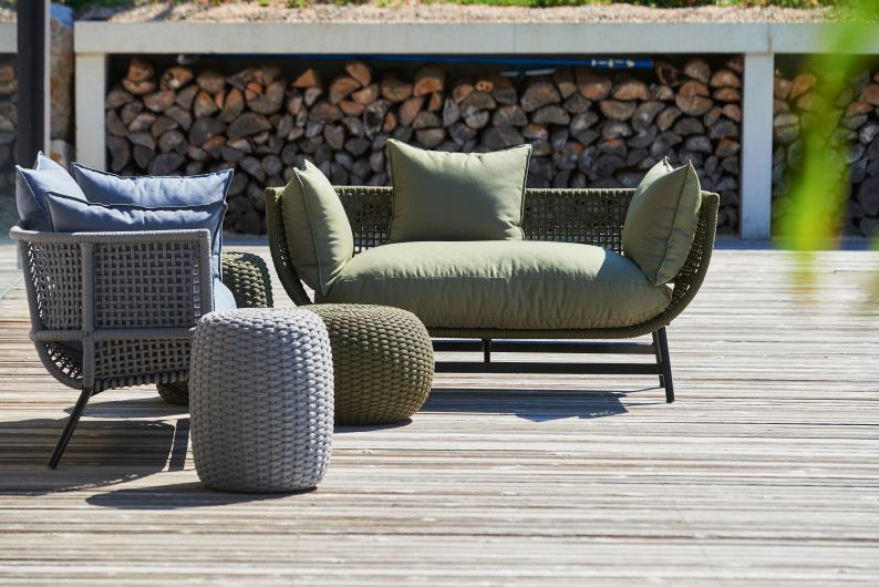 Olivefarbener Jan Kurtz Lounge Sessel für den Außenbereich mit passendem Hocker und Kissen.