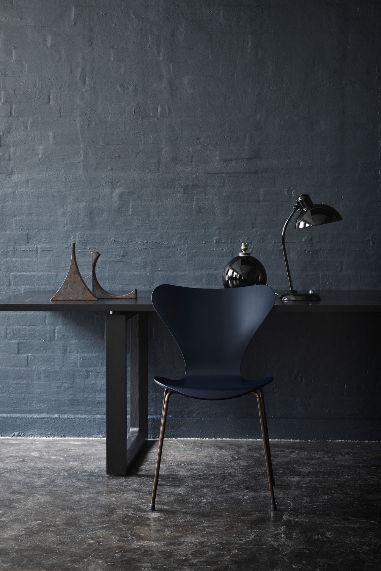 Schwarze KAISER idell 6556 T Tischleuchte von Fritz Hansen auf einem dunklen Schreibtisch.